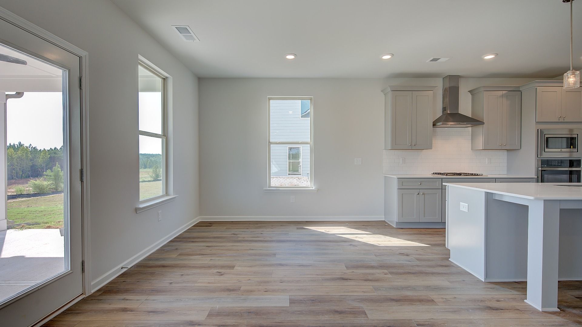 McKinley II open breakfast area with LVP flooring and view of backyard at Brighton in Locust Grove, GA.