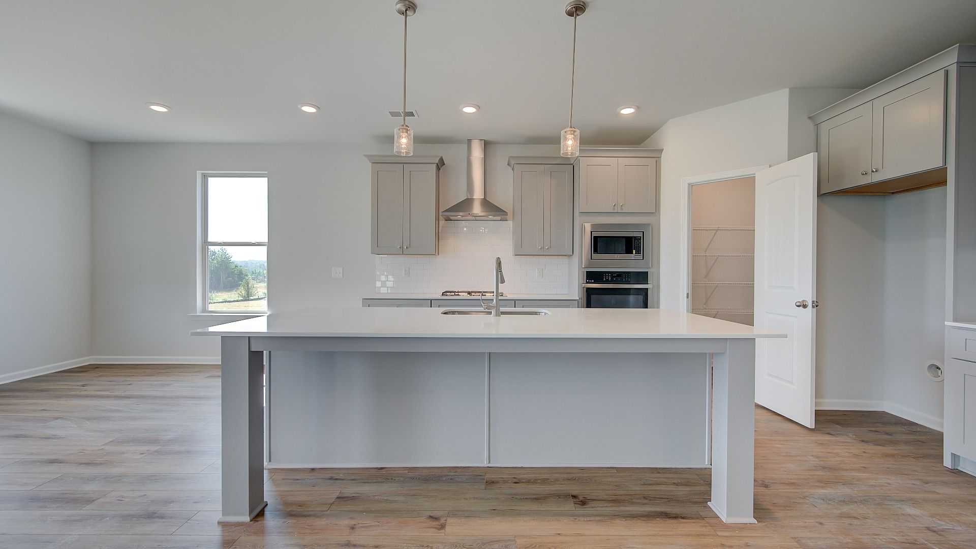Open-concept kitchen with white cabinetry, white tile backsplash, and large island in the McKinley II at Brighton.