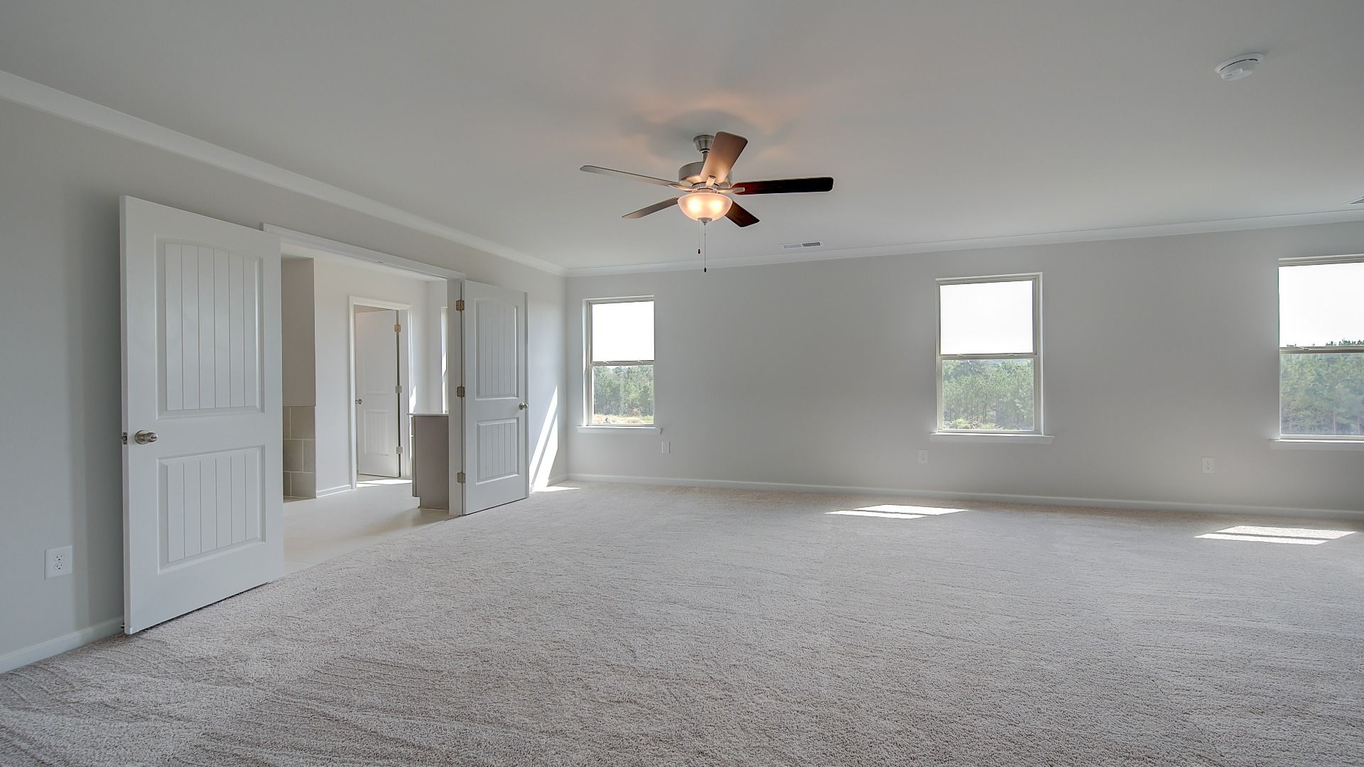 McKinley II expansive primary suite with carpet flooring, natural light, and sitting area at Brighton in Locust Grove, GA.