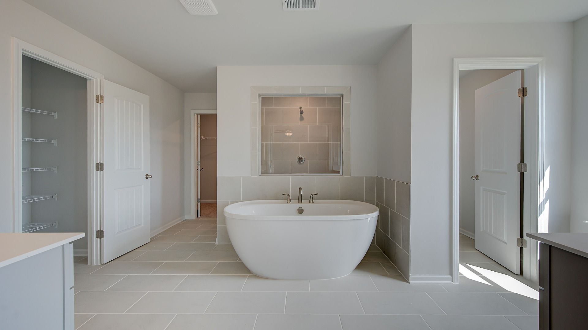 Modern primary bath with tile flooring and freestanding tub in the McKinley II at Brighton in Locust Grove, GA.