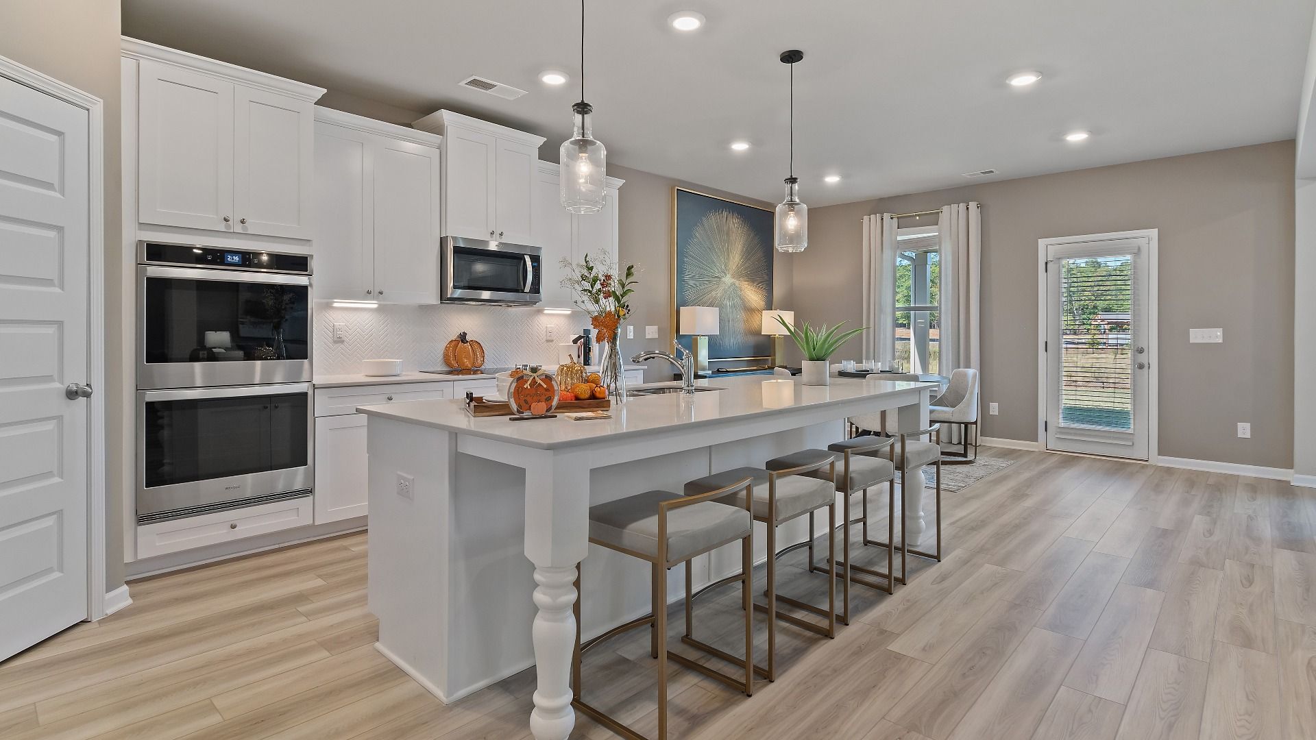Open-concept kitchen with white cabinetry, white tile backsplash, and large island in the McKinley II at Brighton.