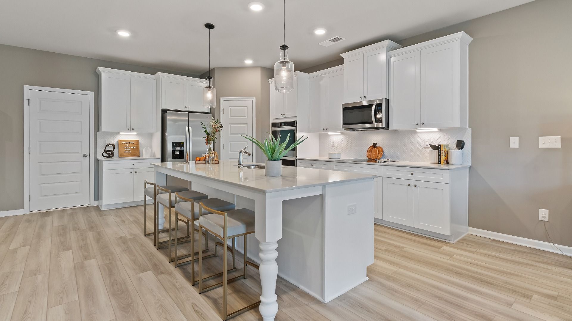 McKinley II modern kitchen with bright white cabinetry, tile backsplash, and large island with seating at Brighton.