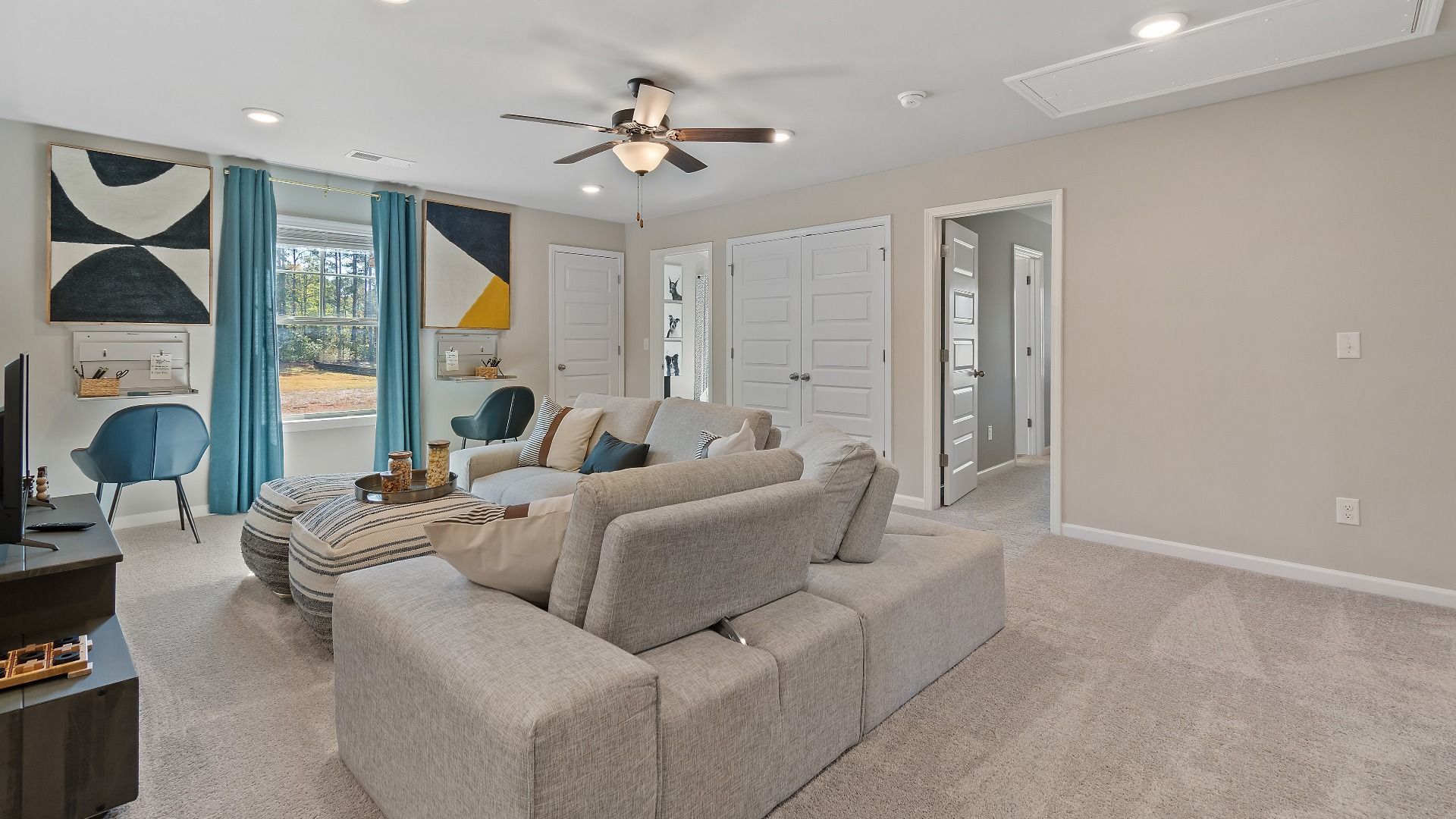 McKinley II spacious loft with carpet flooring, natural light, and ceiling fan light at Brighton in Locust Grove, GA.