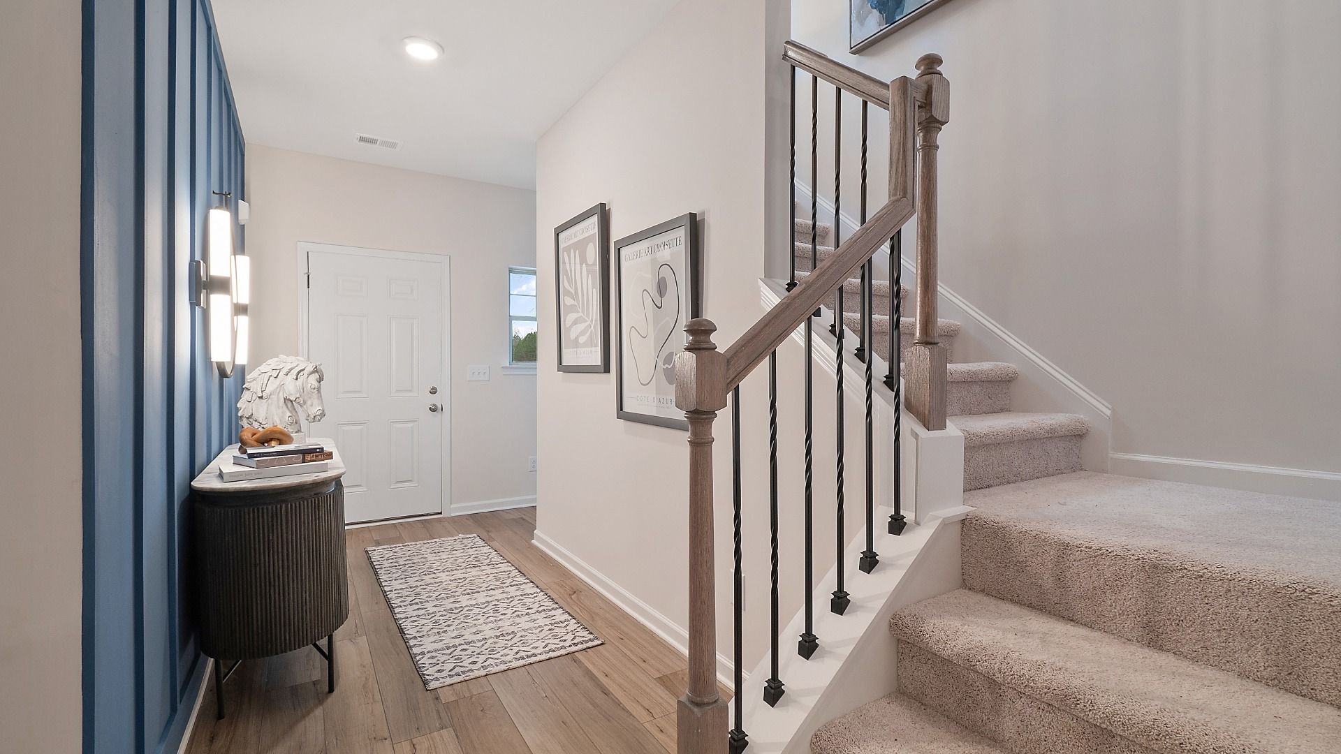 Zoey II open foyer with LVP flooring and carpeted stairs in a welcoming entry at Abbotts Crossing in Conyers, GA.