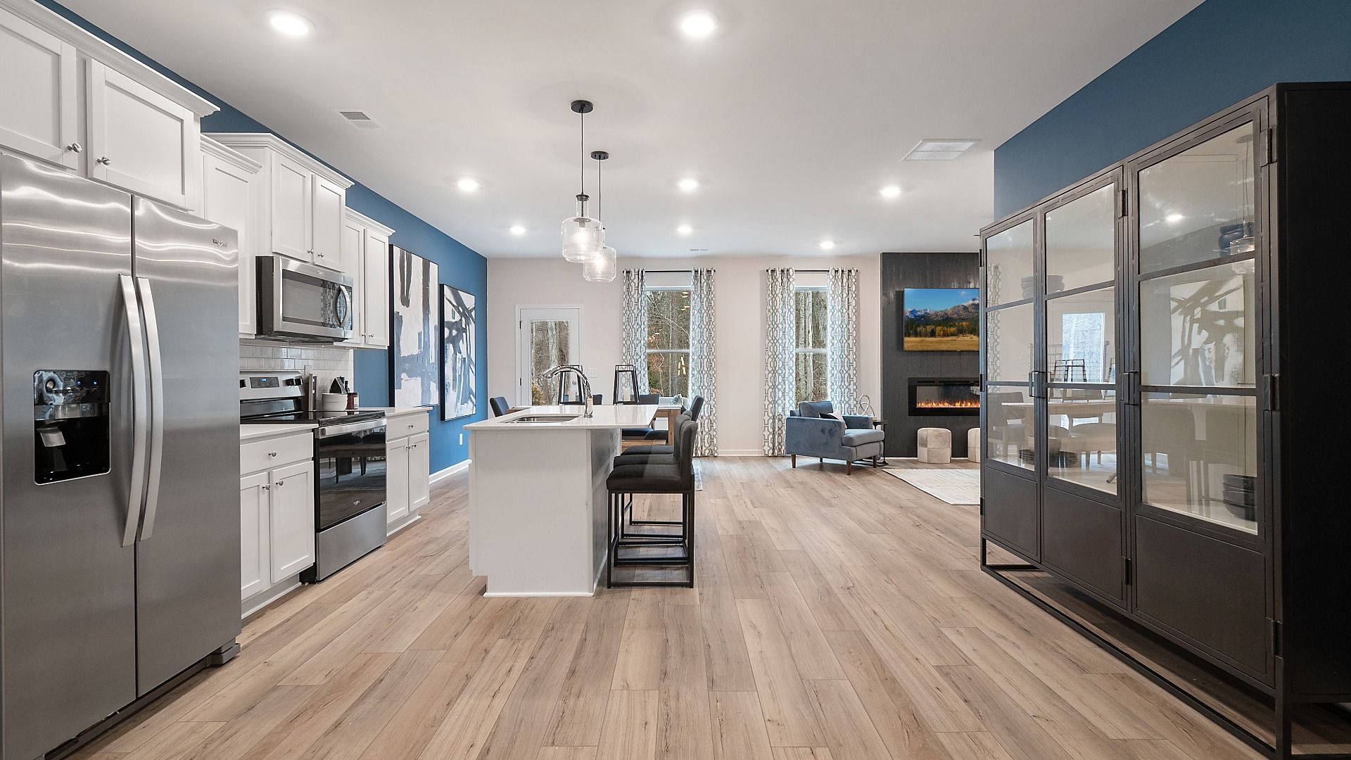 Open-concept kitchen with LVP flooring, expansive island, and stainless appliances in the Zoey II plan at Abbotts Crossing.
