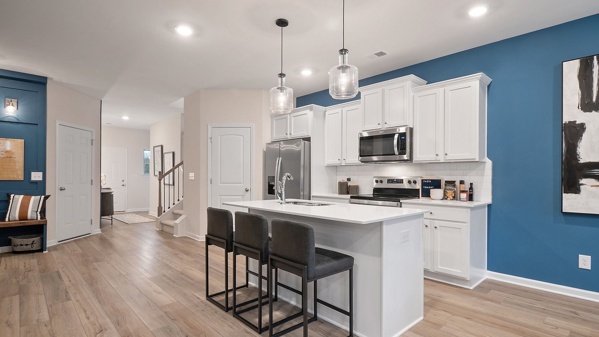 Zoey II bright kitchen with center island, modern white cabinetry, and stainless appliances at Abbotts Crossing.