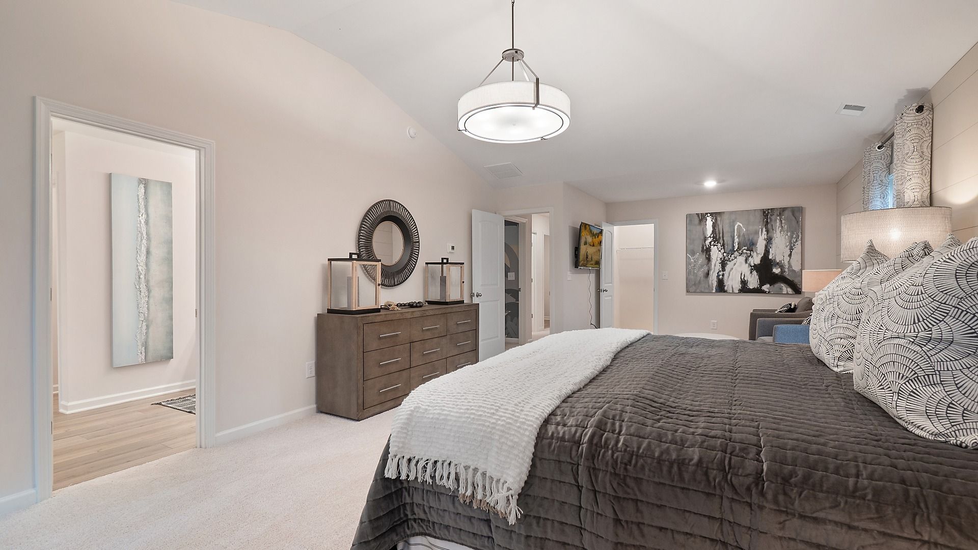 Spacious primary suite featuring carpet flooring and seating area in the Zoey II plan at Abbotts Crossing in Conyers, GA.