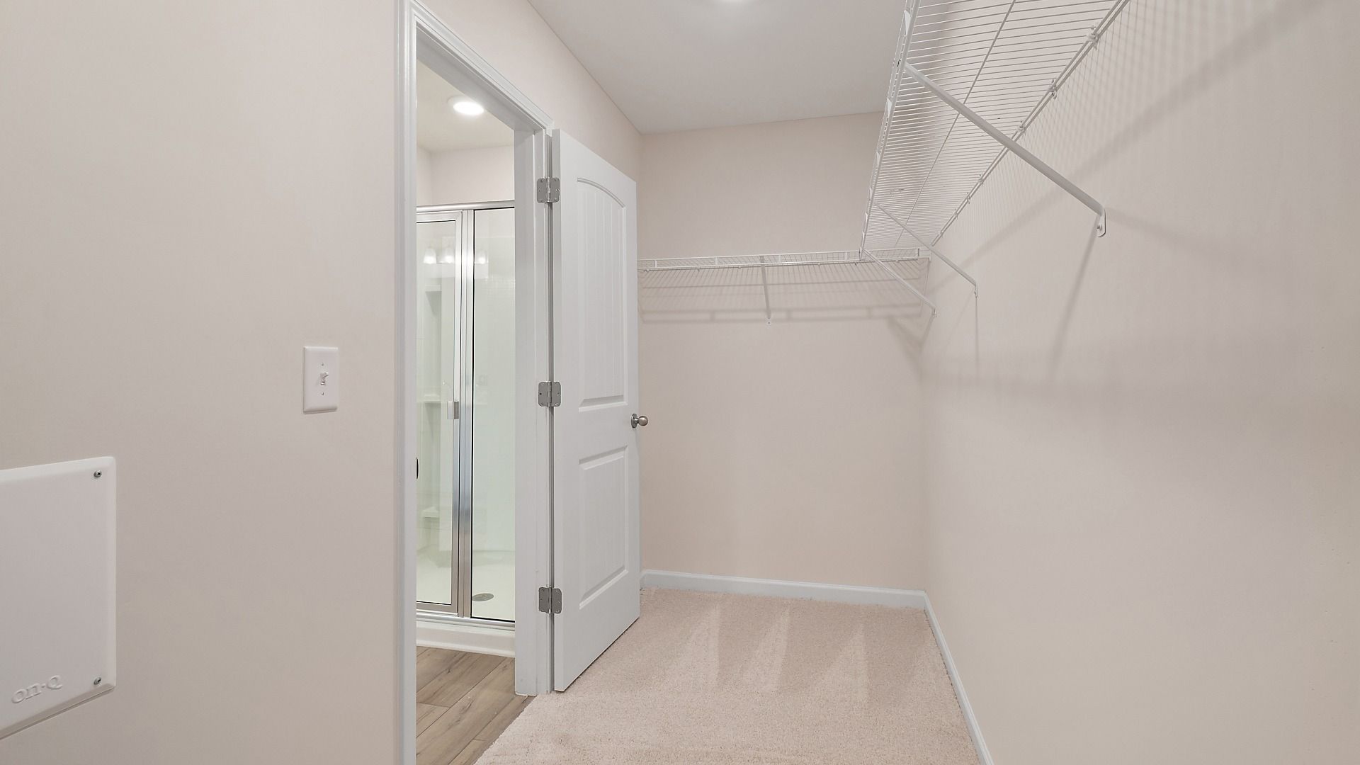 Primary suite closet with built-in shelves and carpet flooring, accessible from the bath in the Zoey II at Abbotts Crossing.