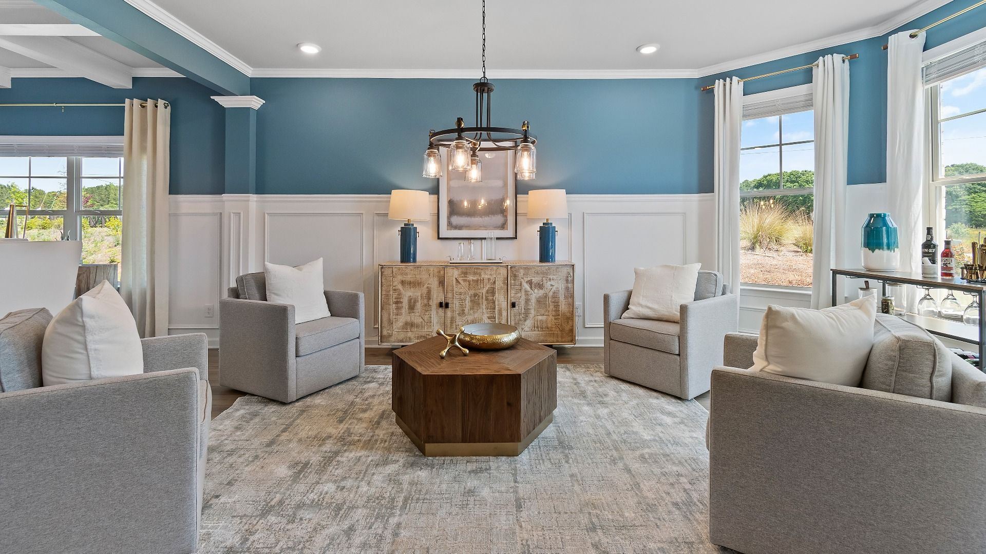 Expansive living room with LVP flooring, abundant natural light, and chandelier lighting in Everest III at Berkeley Lakes.