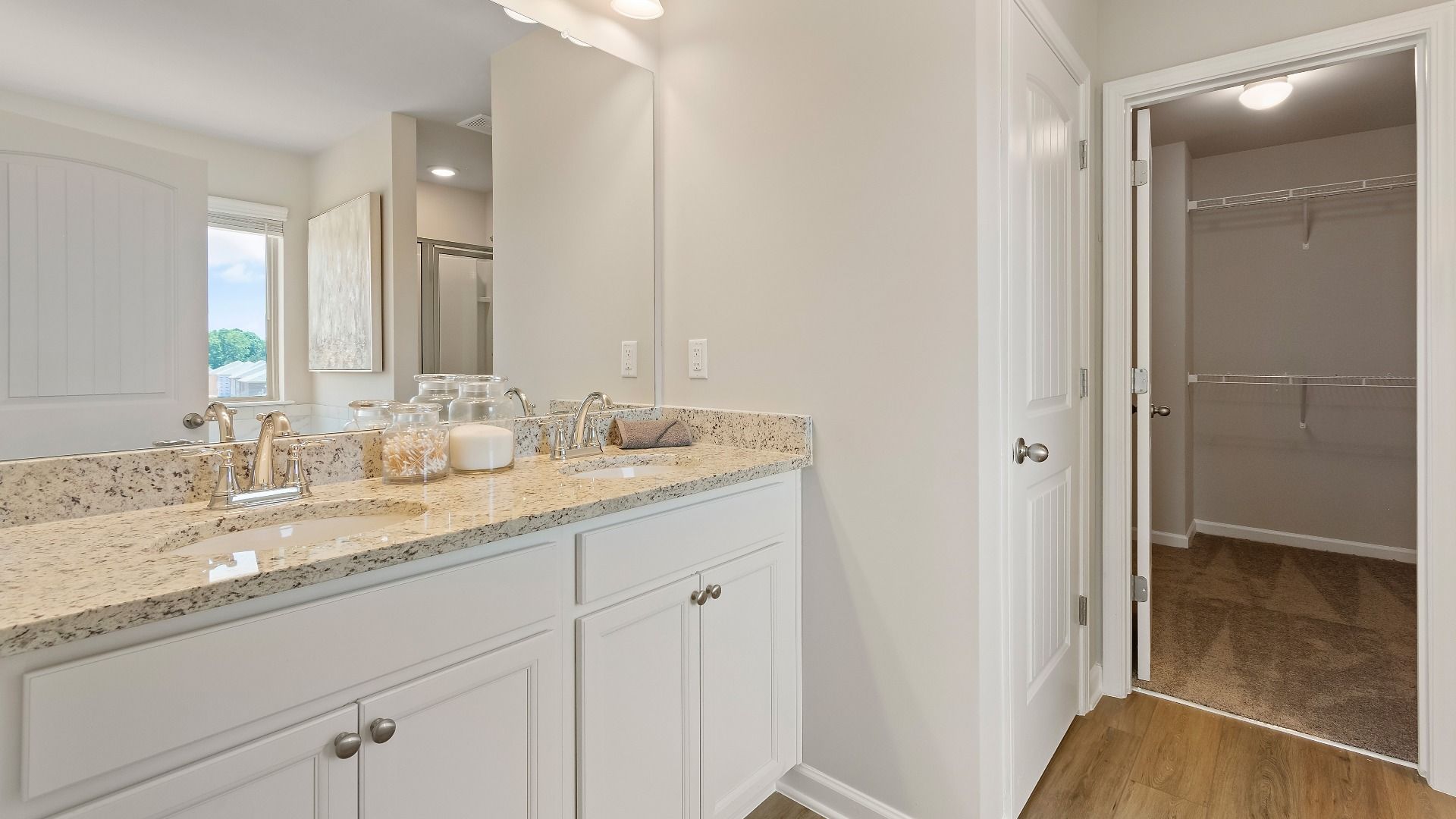 Primary bath with dual vanities, LVP flooring, and a walk-in closet in the Everest III at Berkeley Lakes in Locust Grove, GA.