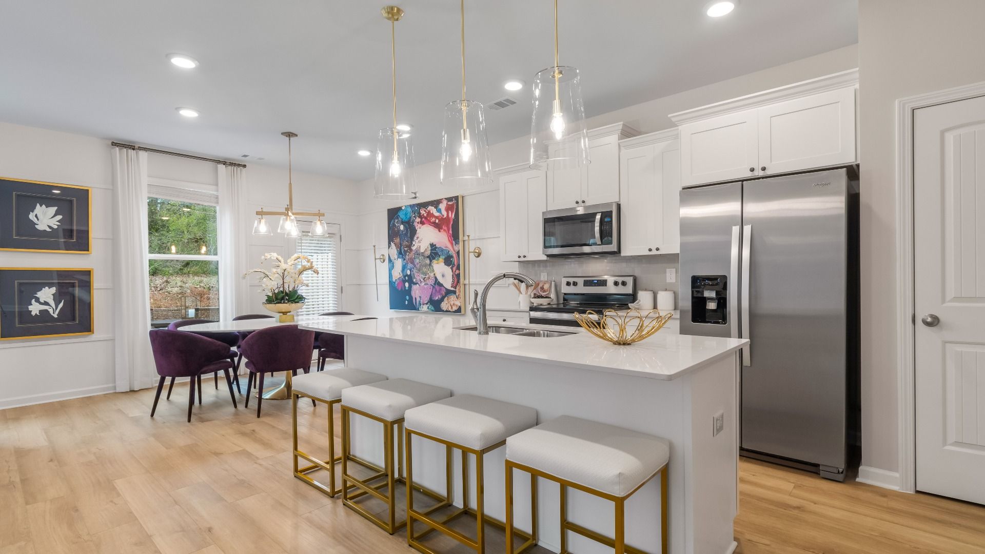 Modern white kitchen with a large island and connected view into the breakfast area in Diamante in Stockbridge, GA.