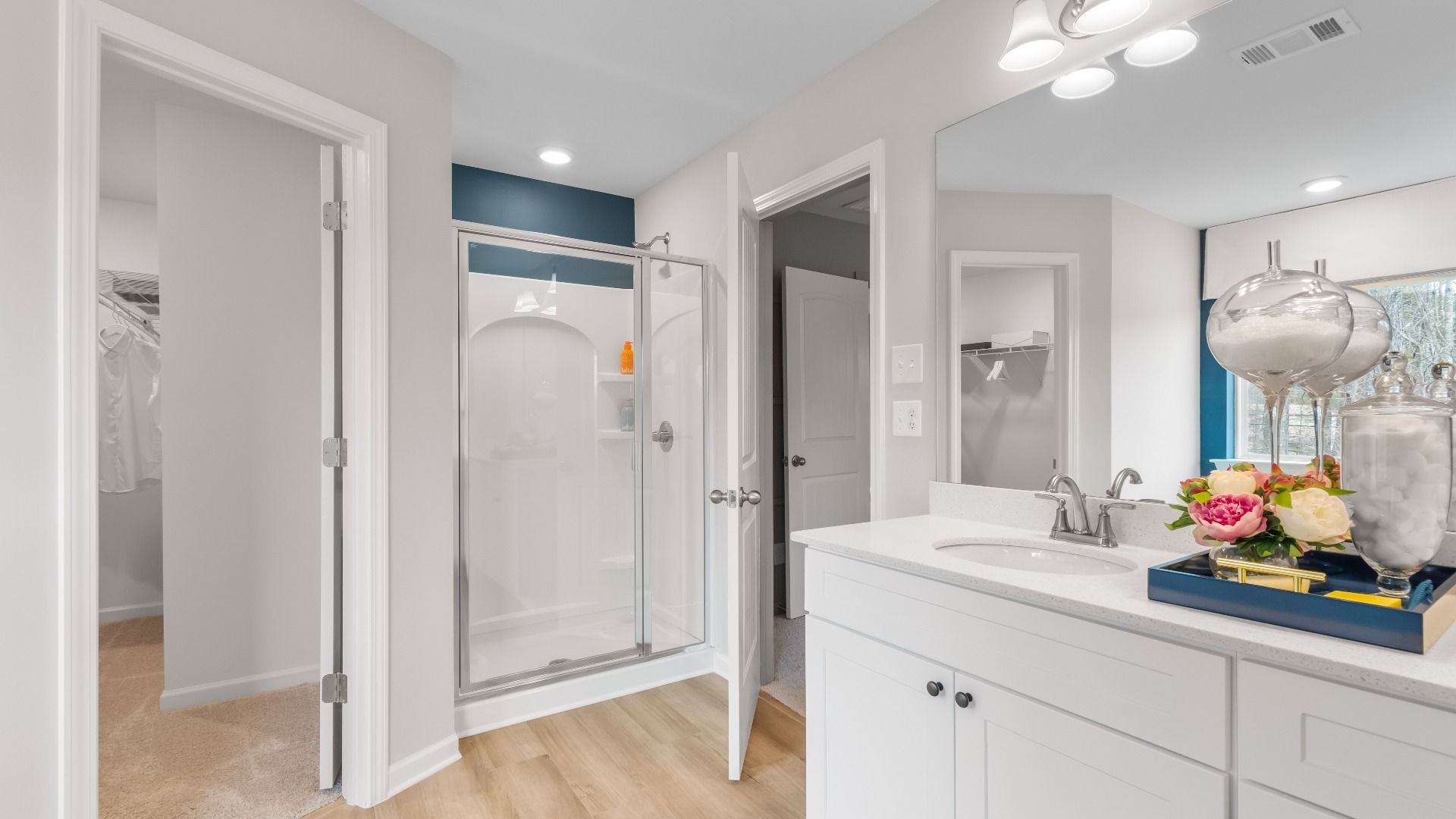 Modern primary bathroom featuring a glass-enclosed shower, double vanity, and walk-in closets in Diamante in Stockbridge, GA.