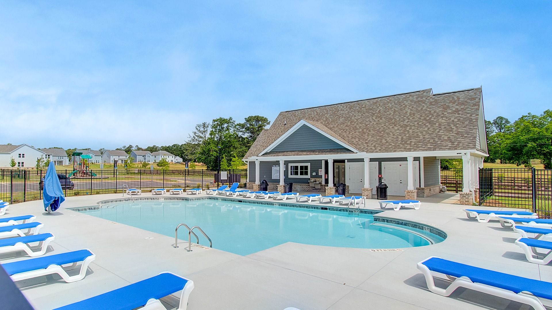 Outdoor community pool with seating and lounge chairs at Cooper Park in McDonough, GA.