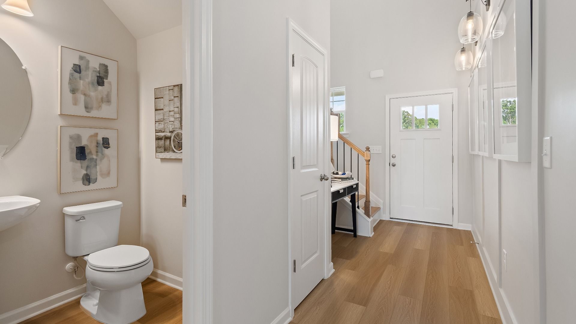 Millhaven foyer with LVP flooring, staircase, and entry to first-floor powder room at Abbotts Crossing in Conyers, GA.