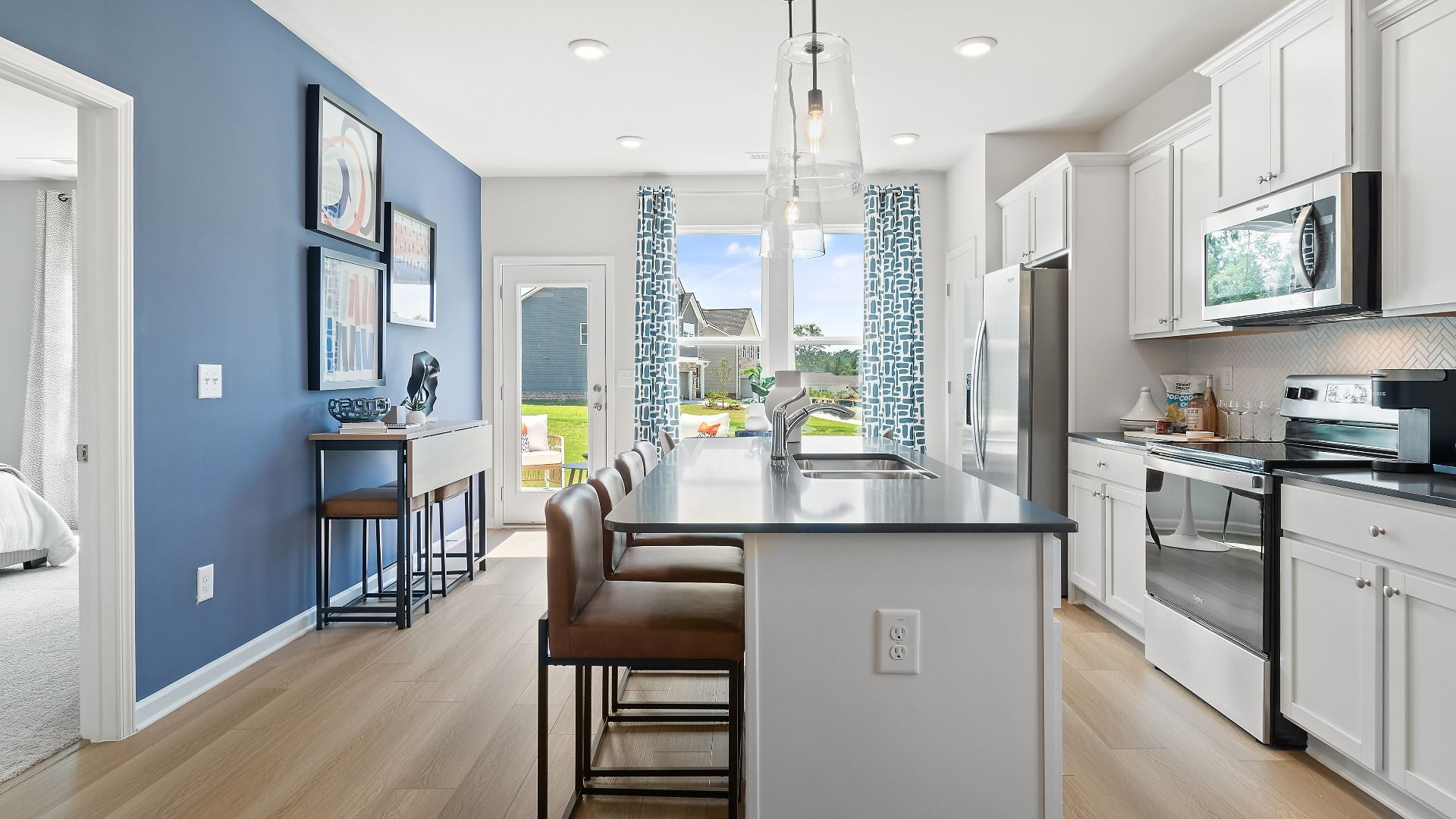 Millhaven kitchen with white cabinetry, center island, and stainless appliances at Abbotts Crossing in Conyers, GA.