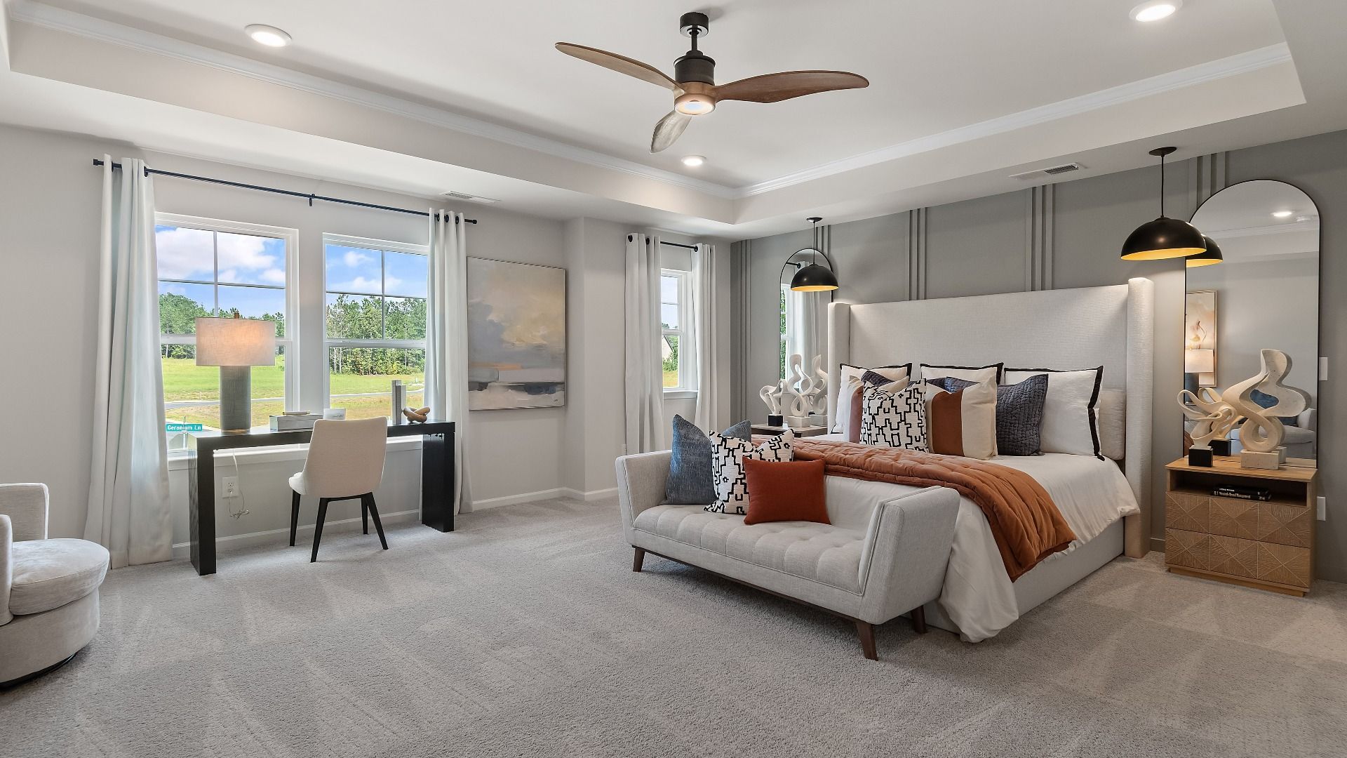 Spacious primary suite with tray ceiling, carpet flooring, and large windows in Millhaven plan at Abbotts Crossing.