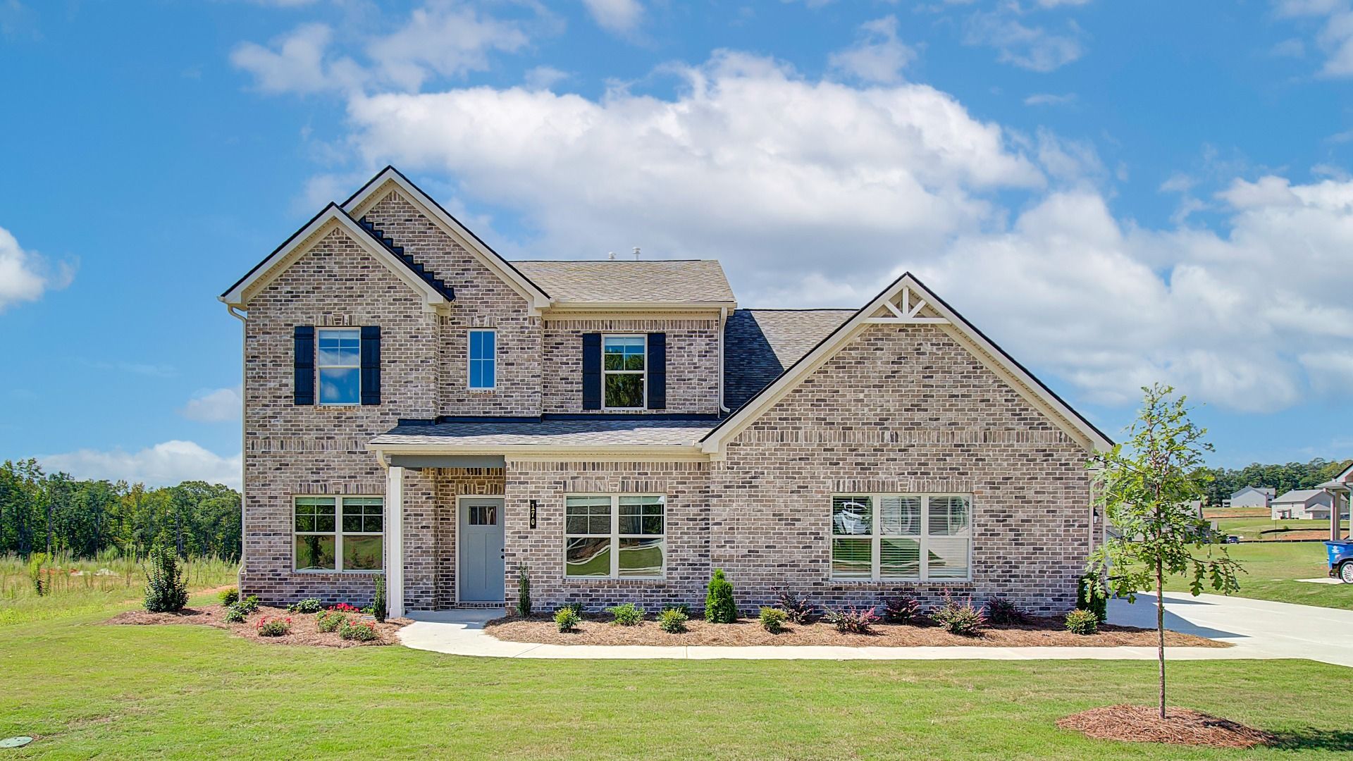 Rainier 4-sided brick new construction single family home with front yard area and side-entry garage in McDonough, GA.