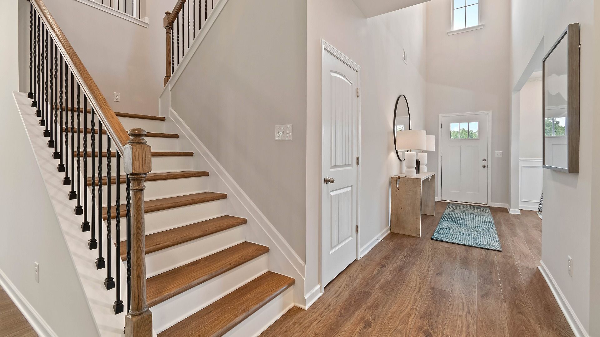 Stairs with LVP flooring, modern open black railing, and wood top rail in the Isabella II at Adagio in Dacula, GA.