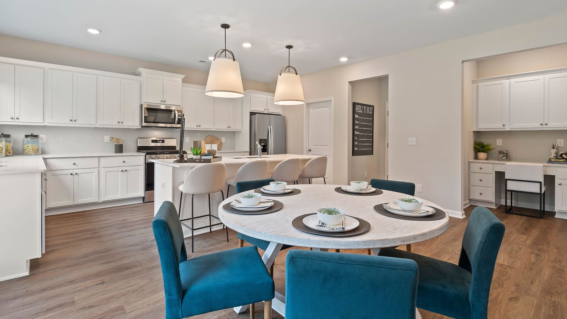 Open breakfast area with pendant lighting and view into bright kitchen in the Isabella II at Adagio in Dacula, GA.