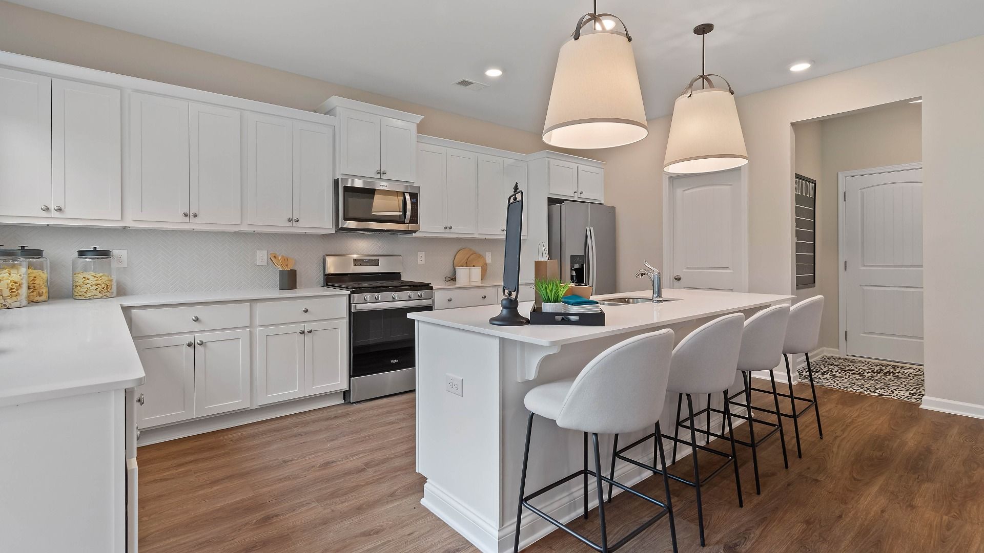 Bright kitchen with modern finishes, white cabinetry, and a center island in the Isabella II at Adagio in Dacula, GA.