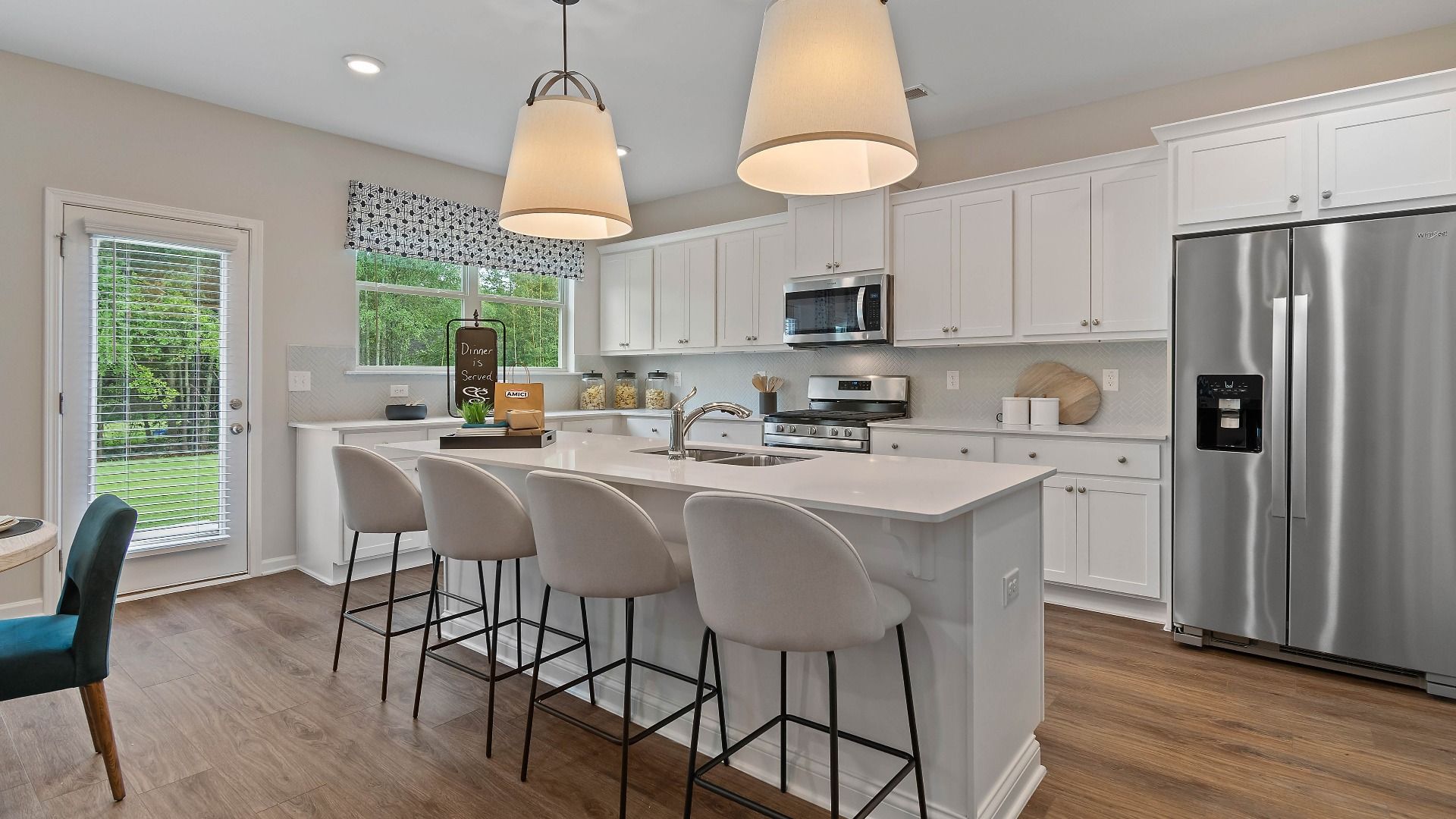 Expansive kitchen featuring a center island with seating and modern tile backsplash in the Isabella II at Adagio.