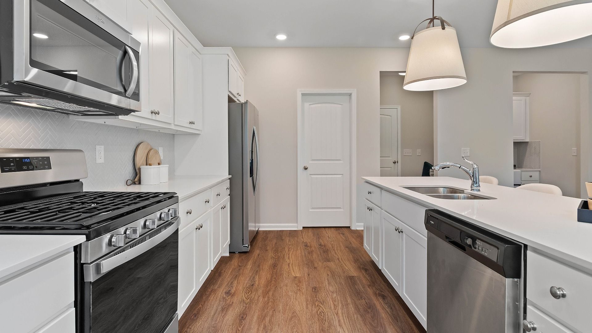 Modern kitchen with white cabinetry, a large island, pendant lighting, and stainless appliances in the Isabella II at Adagio.