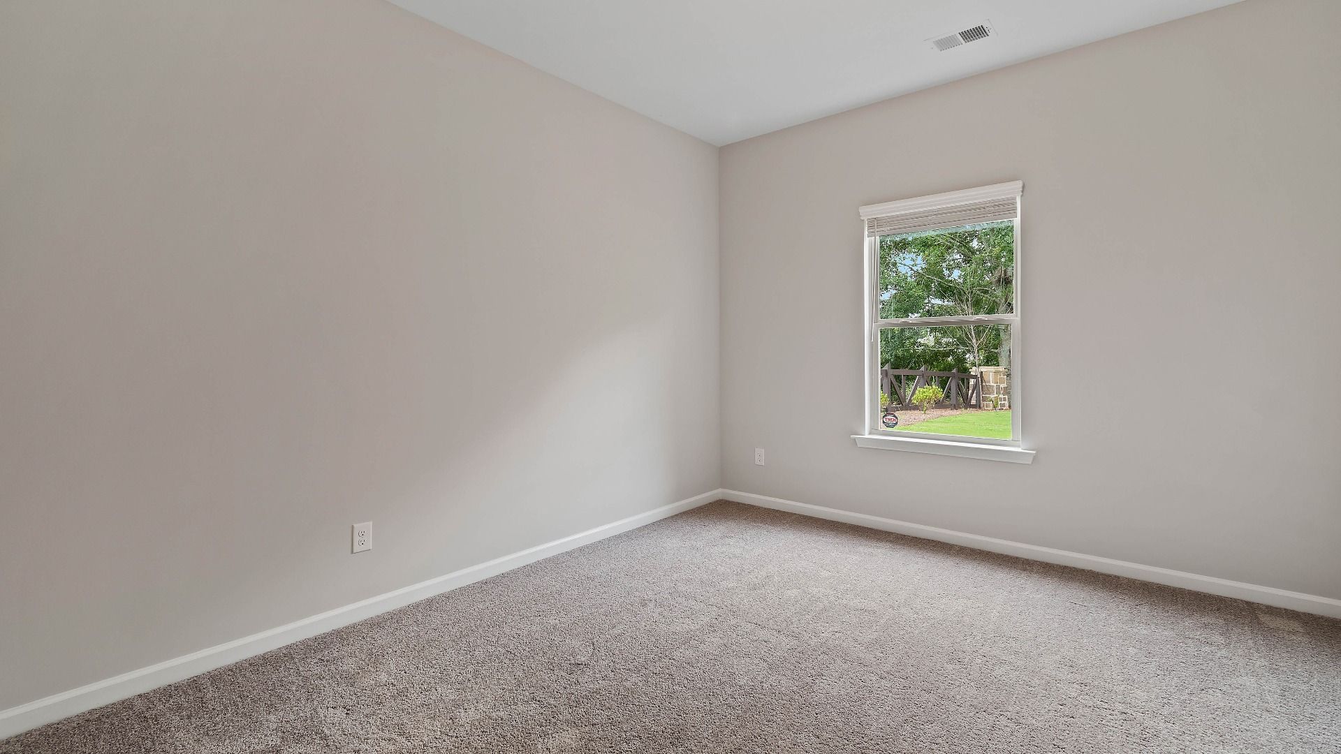 Cozy secondary bedroom with carpet flooring and a window providing natural light in the Isabella II at Adagio in Dacula, GA.