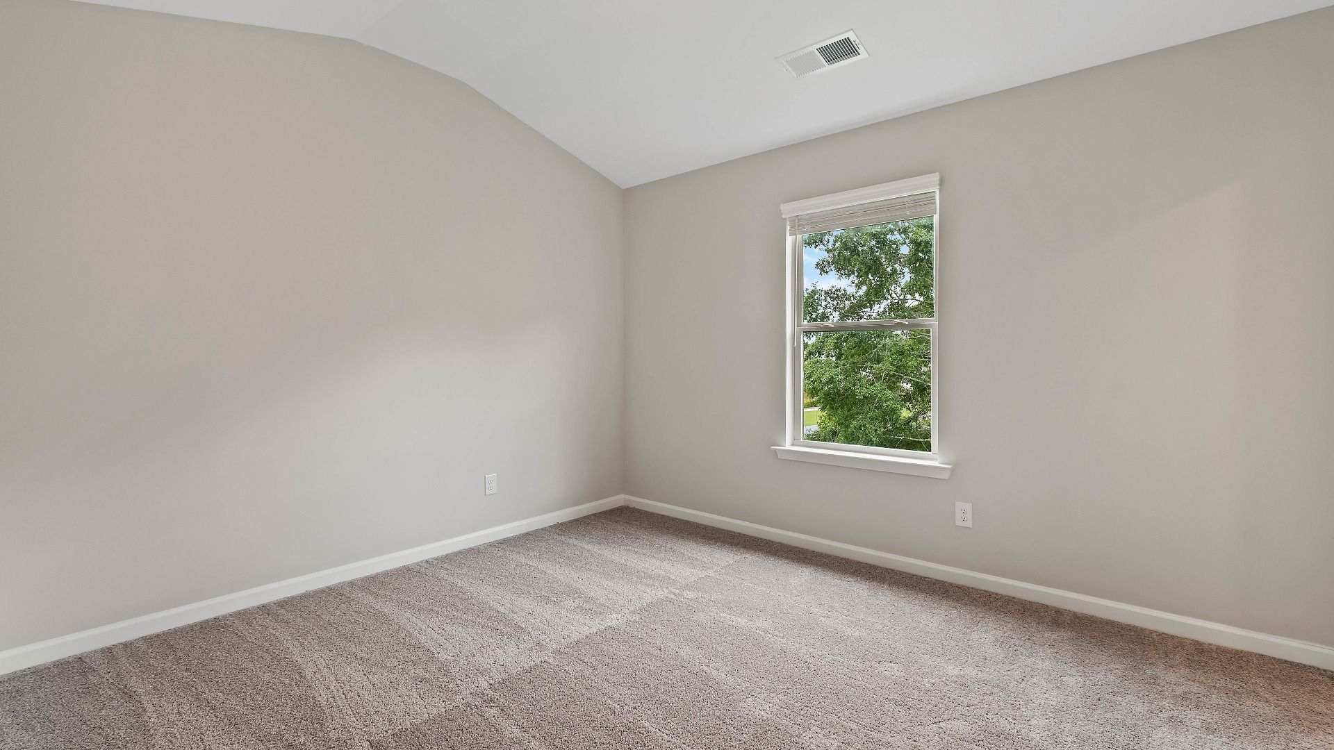 Cozy secondary bedroom with carpet flooring and a window providing natural light in the Isabella II at Adagio in Dacula, GA.