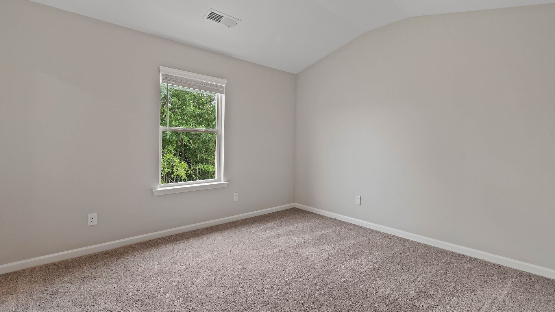 Cozy secondary bedroom with carpet flooring and a window providing natural light in the Isabella II at Adagio in Dacula, GA.