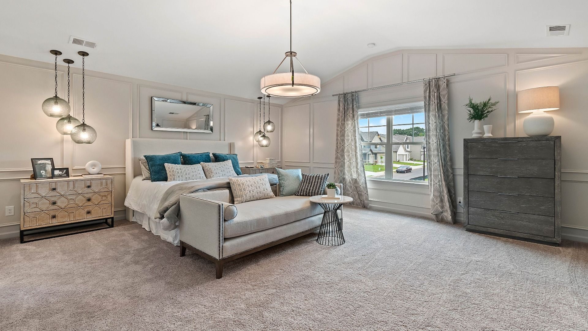 Expansive primary suite with carpet flooring, wall panel molding, and neutral finishes in the Isabella II at Adagio.
