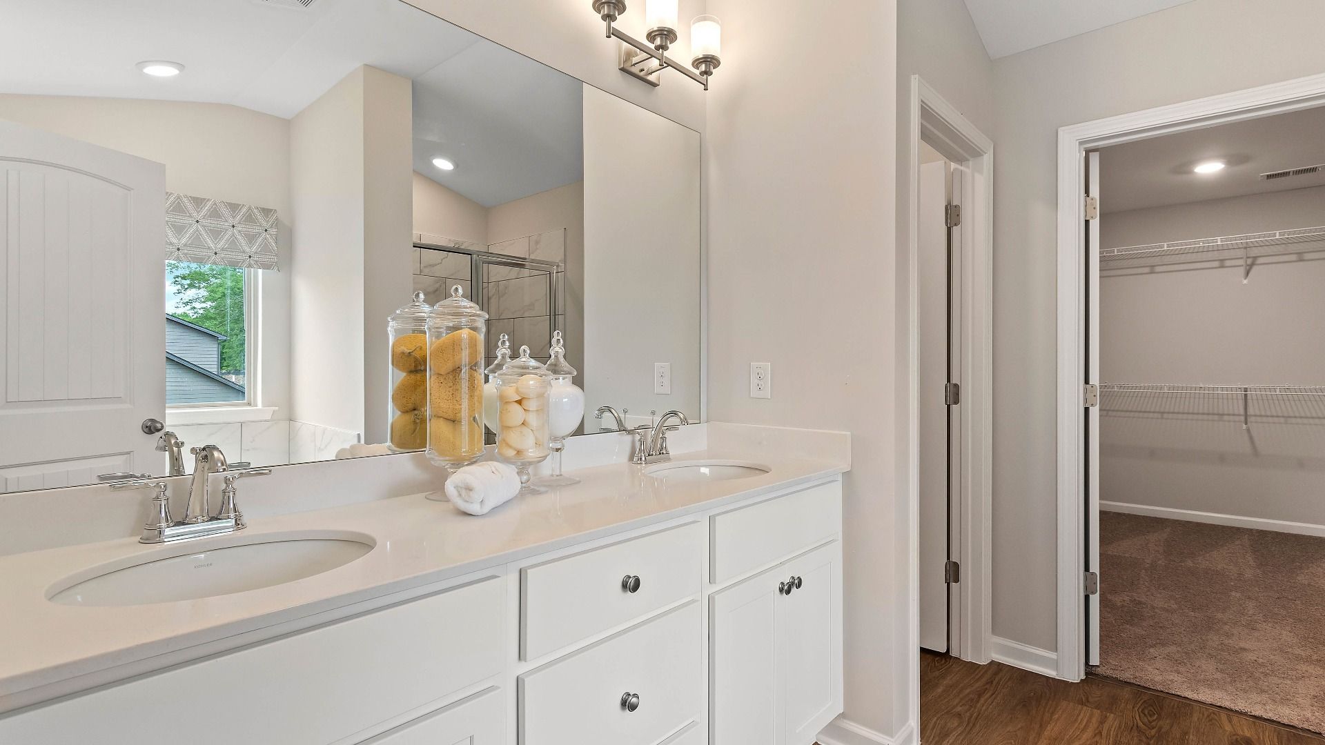 Bright primary bath with double vanity and white modern finishes in the Isabella II at Adagio in Dacula, GA.
