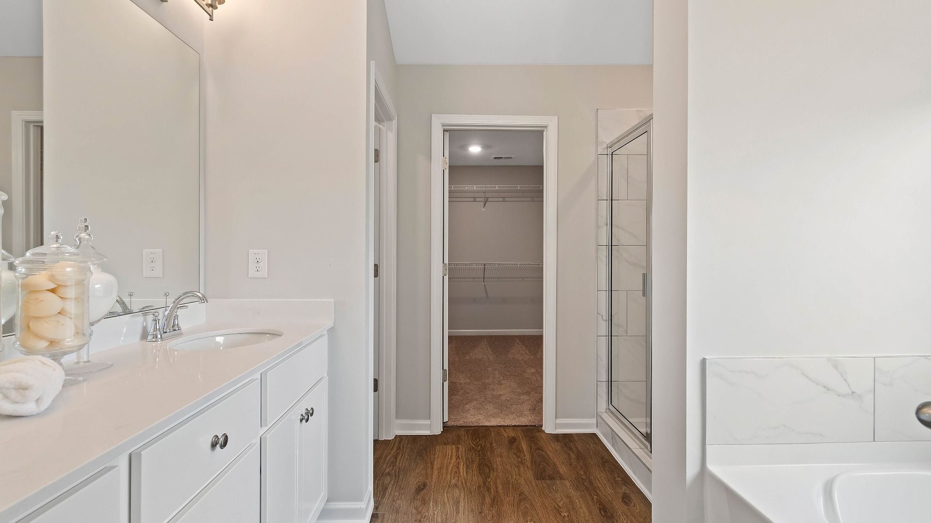 Primary bath with double vanity, tiled shower and bath, and LVP flooring in the Isabella II at Adagio in Dacula, GA.