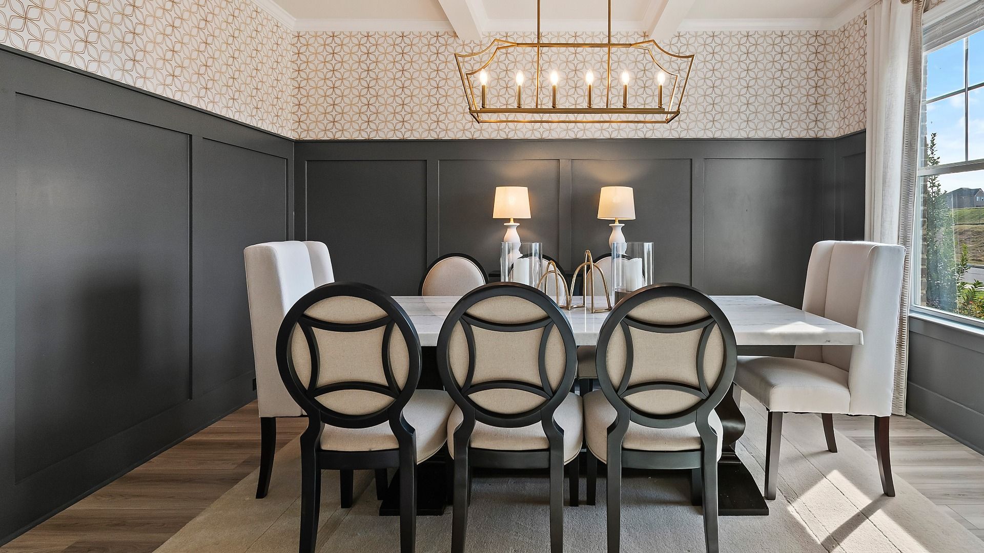Formal dining room with elegant chandelier, large windows, and modern décor in new construction home at Adagio in Dacula, GA.
