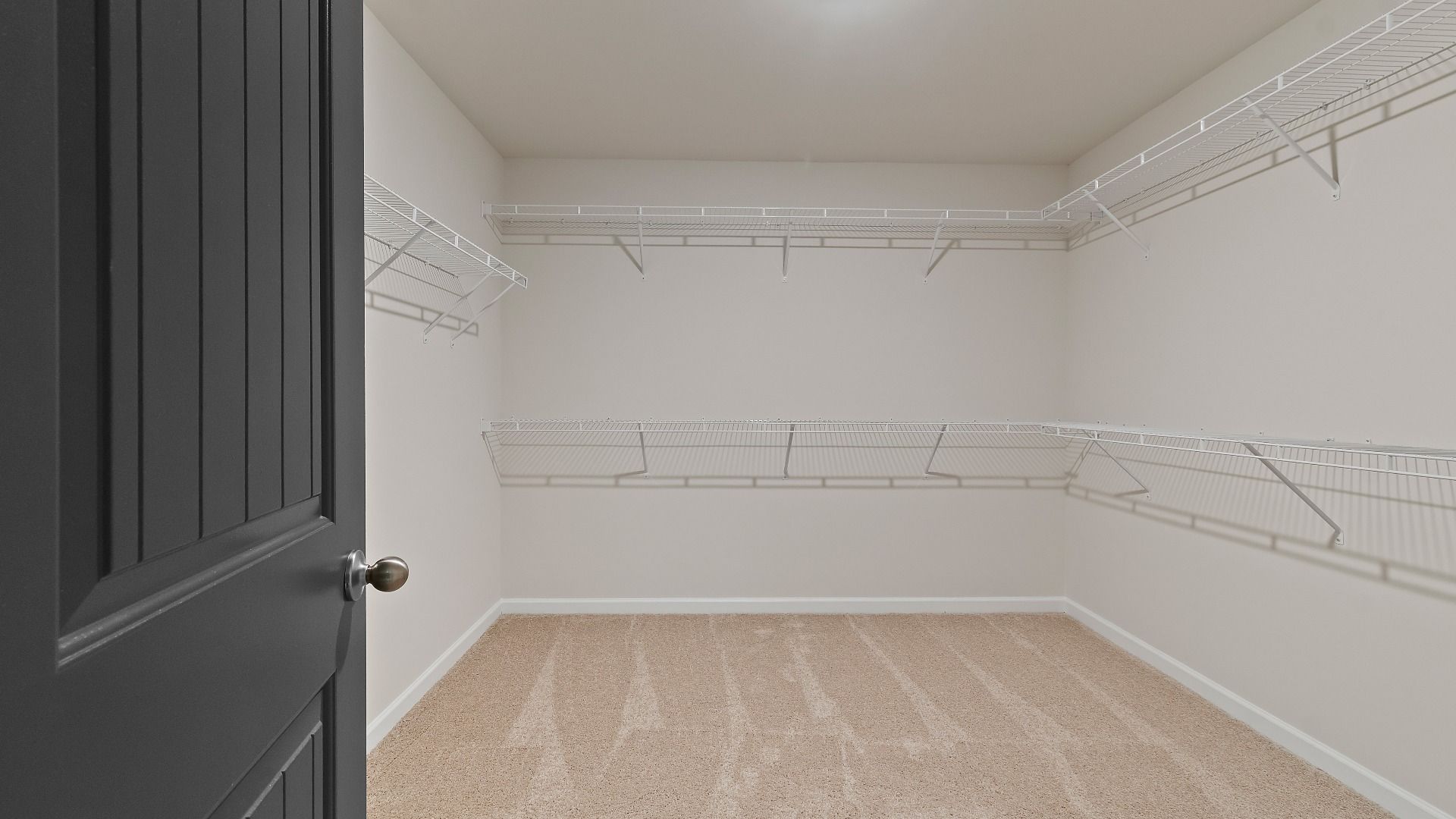 Large primary walk-in closet with organized shelving and hanging space in Abigail II new construction home in Dacula, GA.