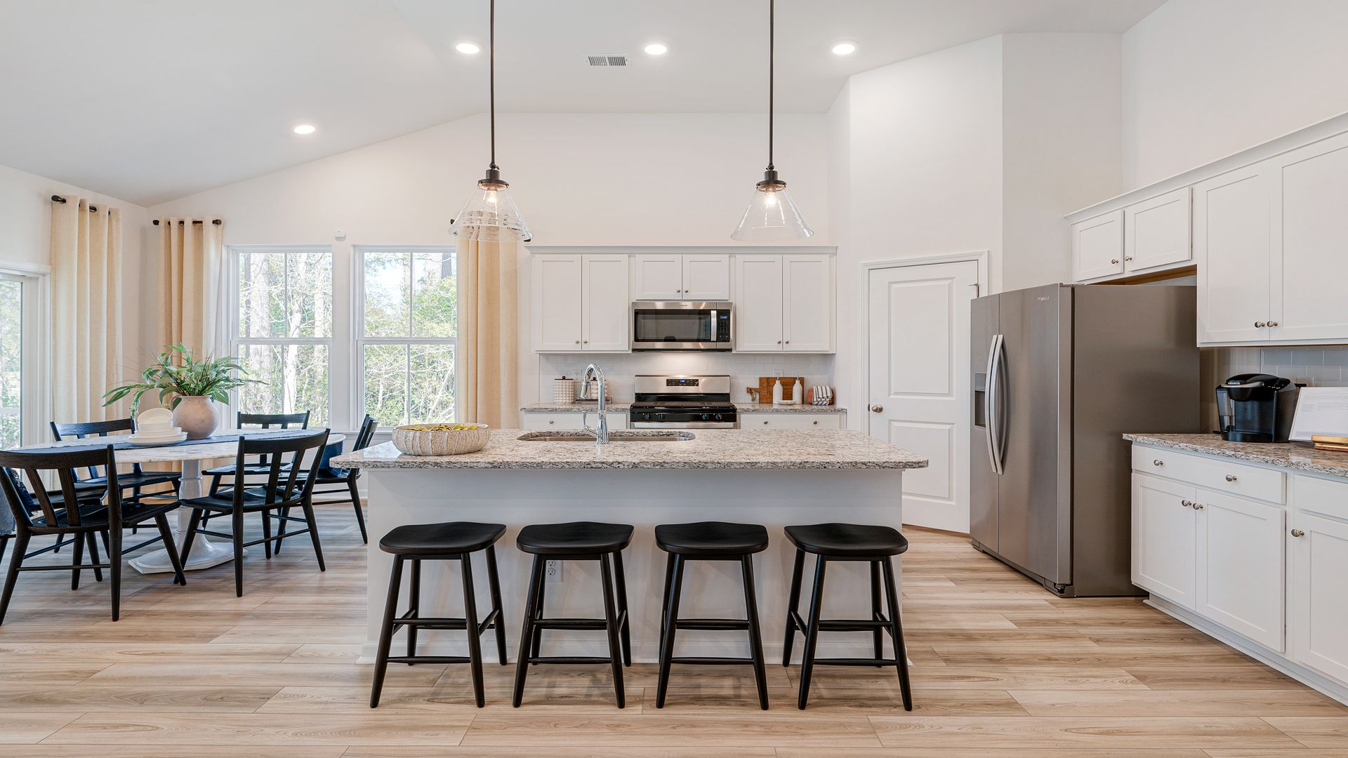 Open kitchen Avondale model in Bluffs at Sun Colony in by DRB homes offering light wood floors and high ceilings