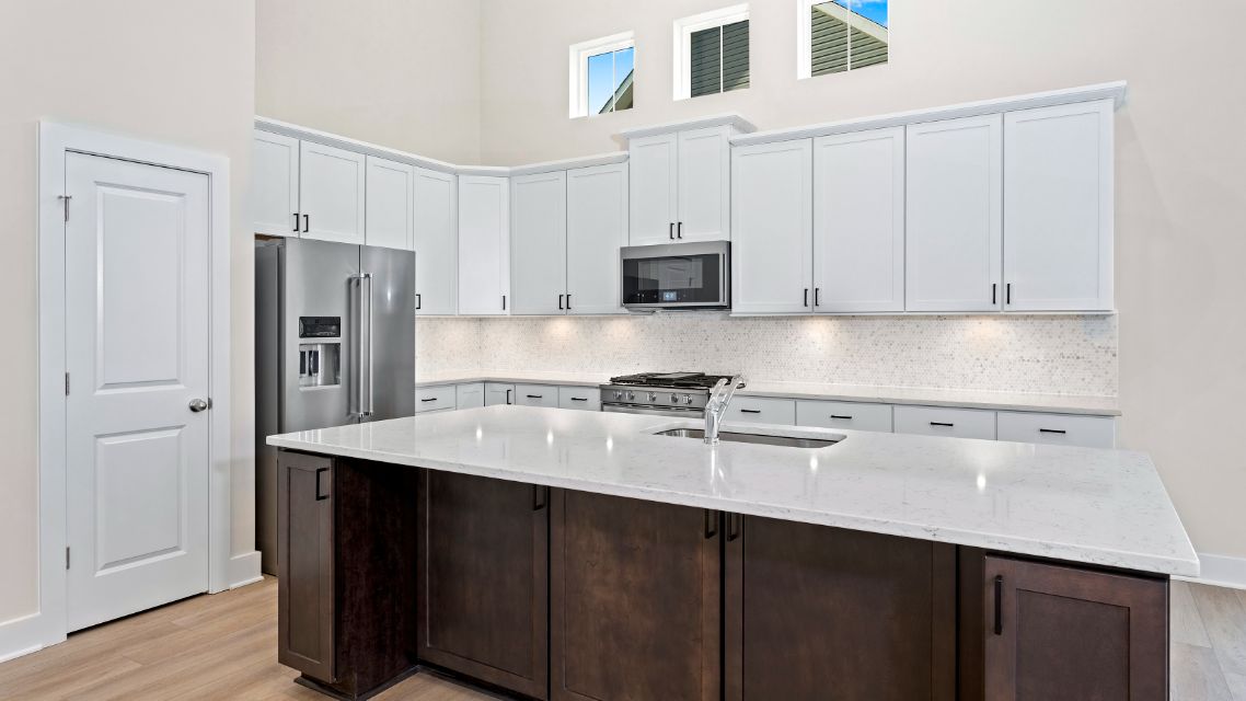 Kitchen with large island, white cabinets, vaulted ceiling and 3 clerestory windows in a DRB Homes Latitude home.