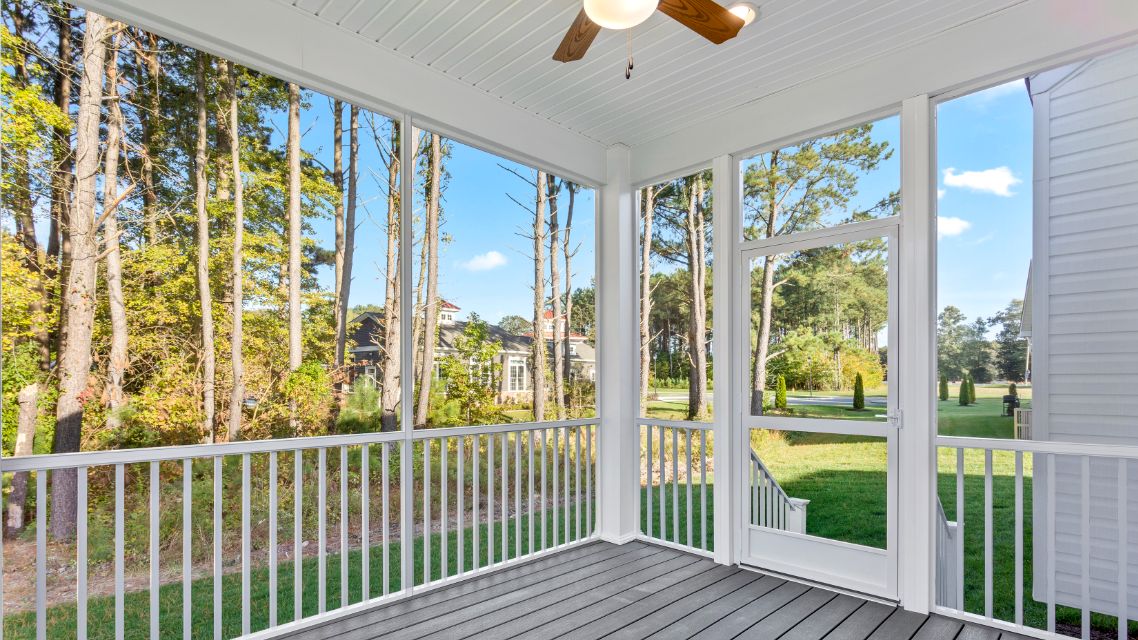 Rear screened porch with white railings and ceiling fan in a DRB Homes Latitude home.