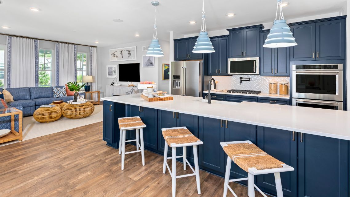 Open kitchen with blue cabinets, white counters and adjacent morning room in a DRB Homes St. Kitts Model Home.