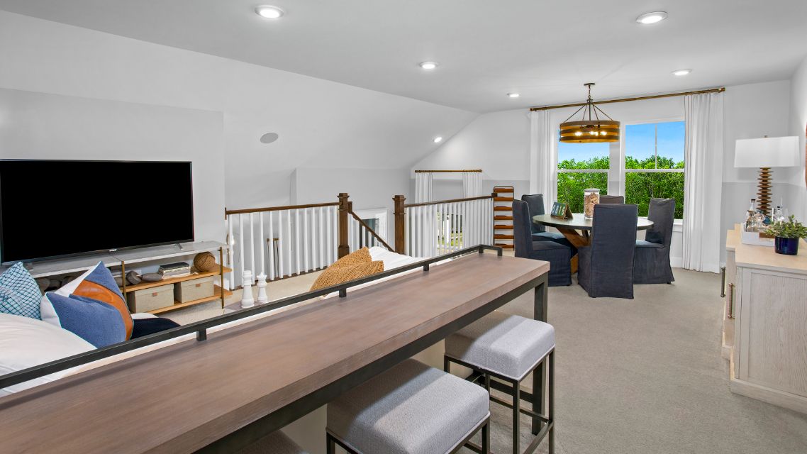 Loft with large double window and several seating areas in a DRB Homes St. Kitts Model Home.