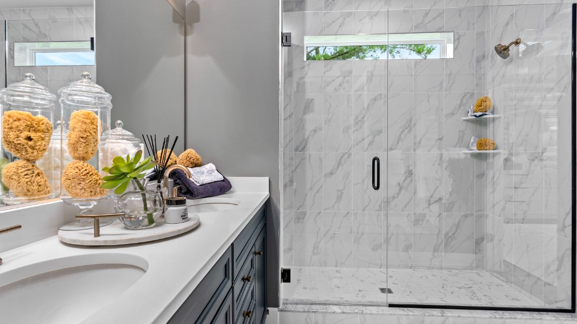 Owner's bathroom with dual sink vanity and large tiled shower with window in a DRB Homes St. Kitts Model Home.