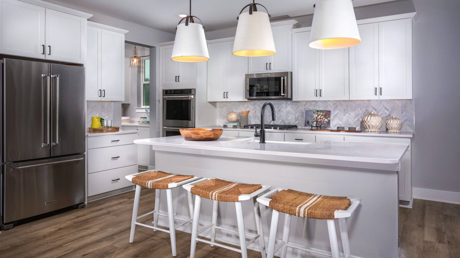 Kitchen with white cabinets, large island and stainless steel appliances in a DRB Homes St. John Model Home.