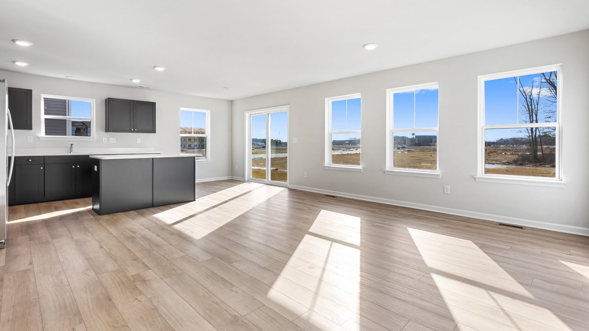 Family room with multiple windows and island kitchen in a DRB Homes Cranberry plan at the Village of College Park community.
