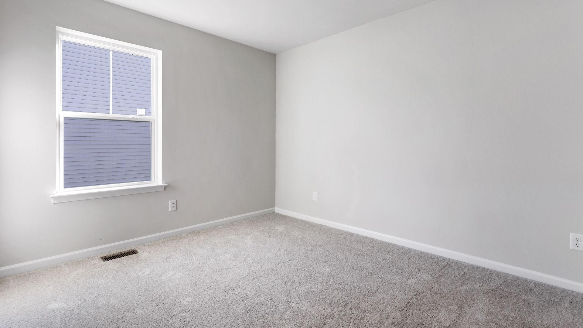 Carpeted secondary bedroom in a DRB Homes Cranberry plan at the Village of College Park community.