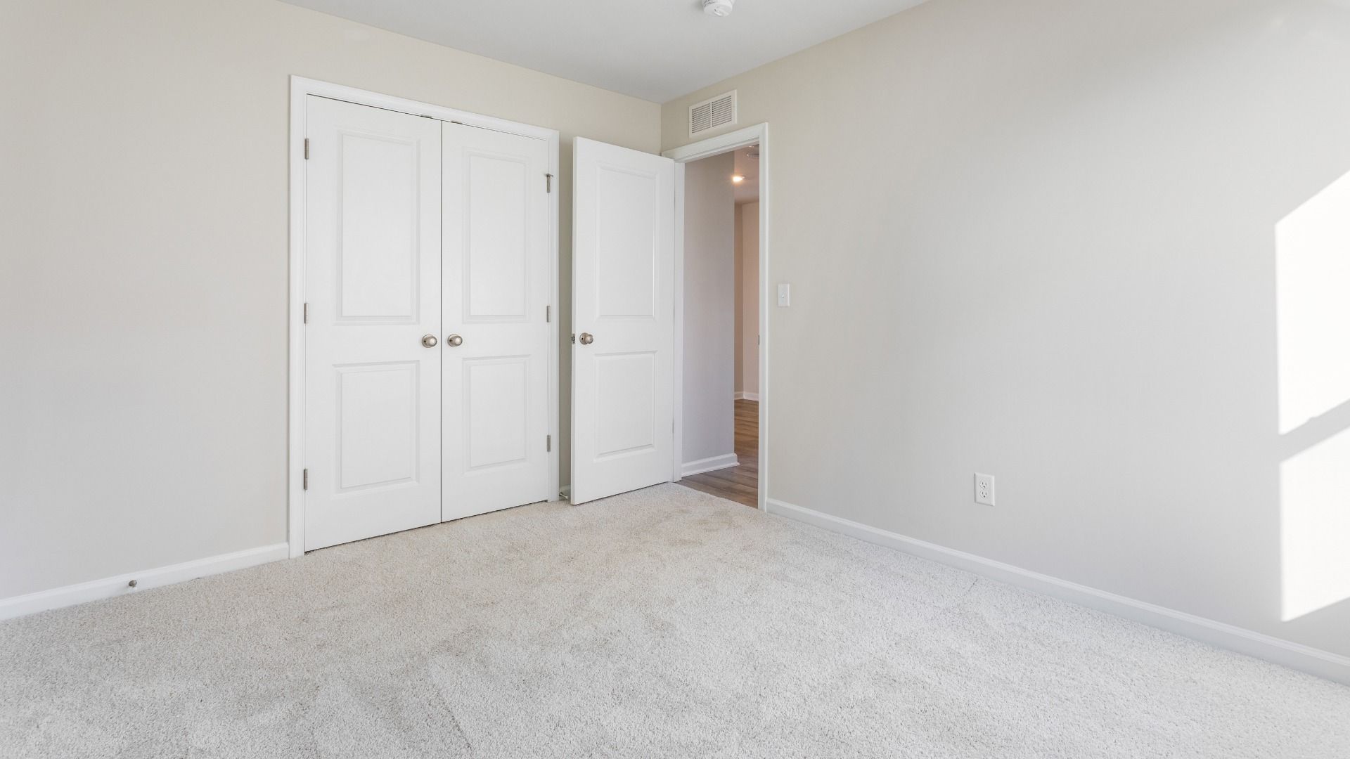 Carpeted secondary bedroom with double door closet in a DRB Homes Cranberry plan at the Village of College Park community.