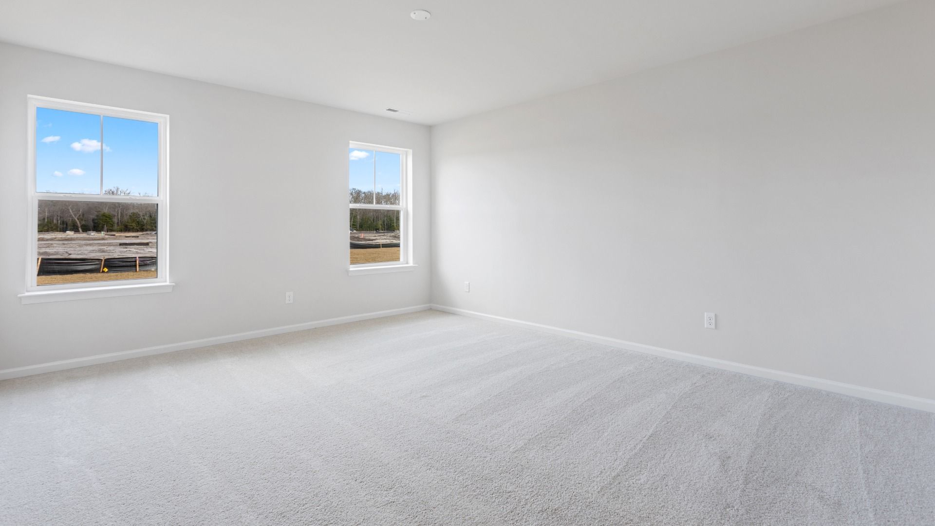 Carpeted owner's suite with 2 large windows in a DRB Homes Edgewood plan at The Village of College Park community.