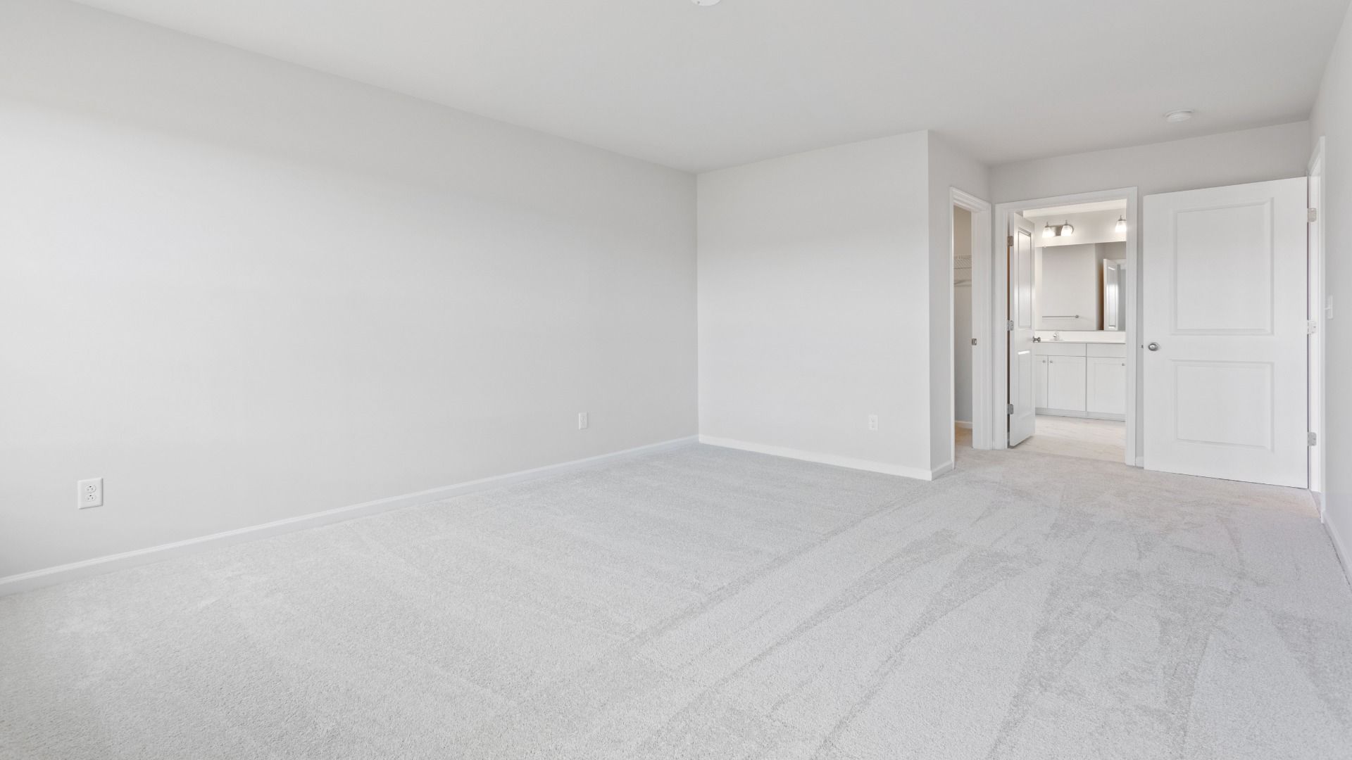 Carpeted owner's suite with en suite bath in a DRB Homes Edgewood plan at The Village of College Park community.