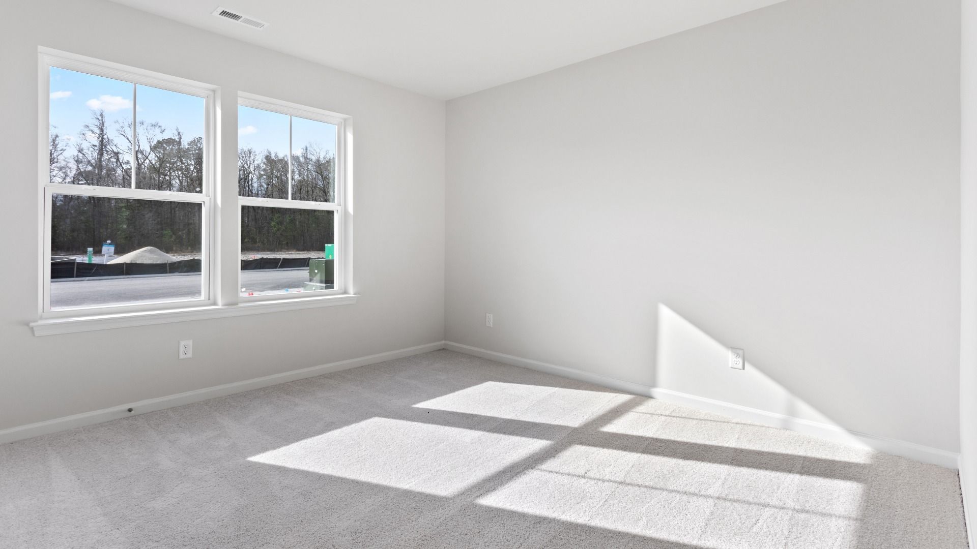 Carpeted secondary bedroom with double window in a DRB Homes Edgewood plan at The Village of College Park community.