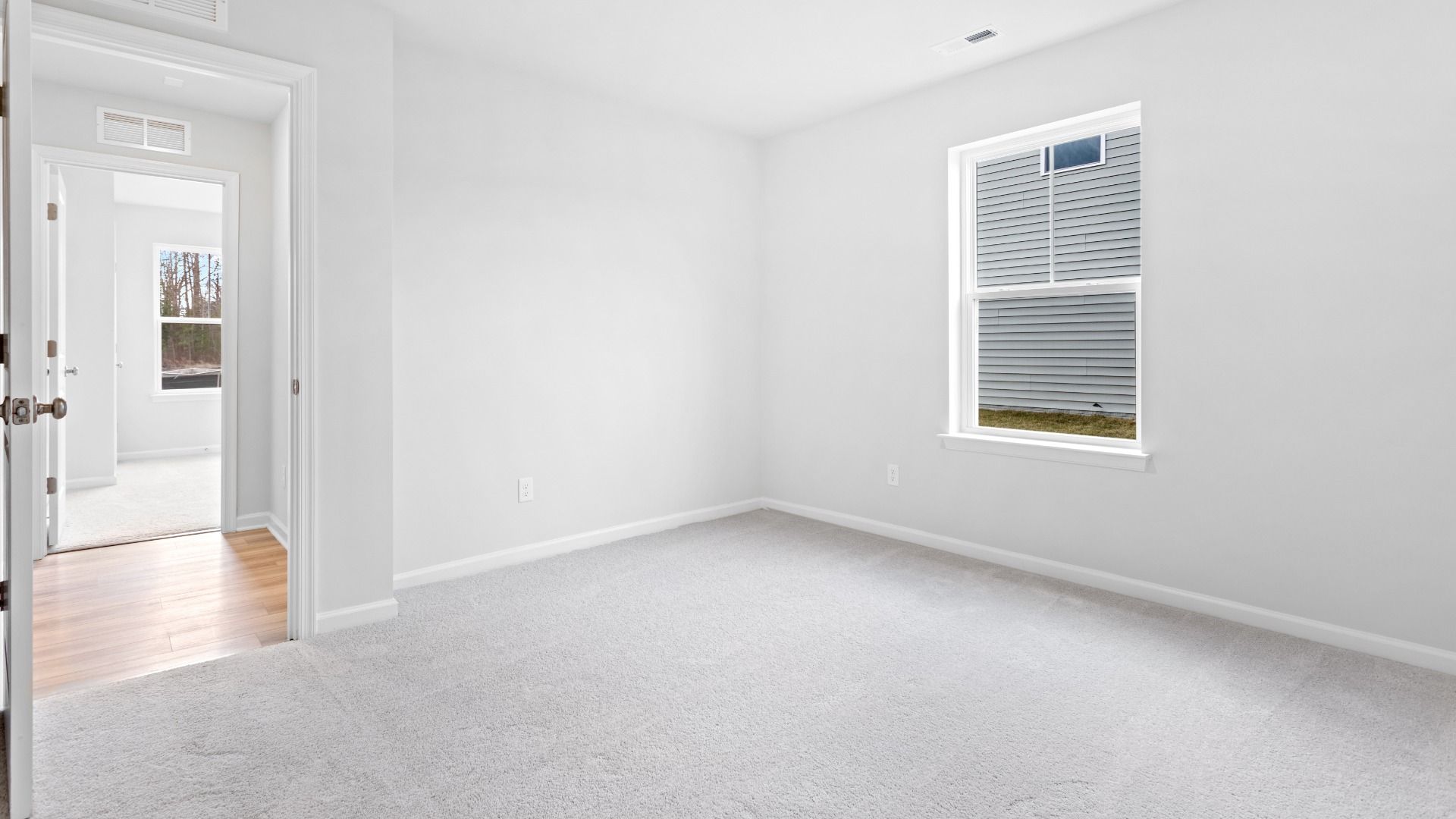 Carpeted secondary bedroom with single window in a DRB Homes Edgewood plan at The Village of College Park community.