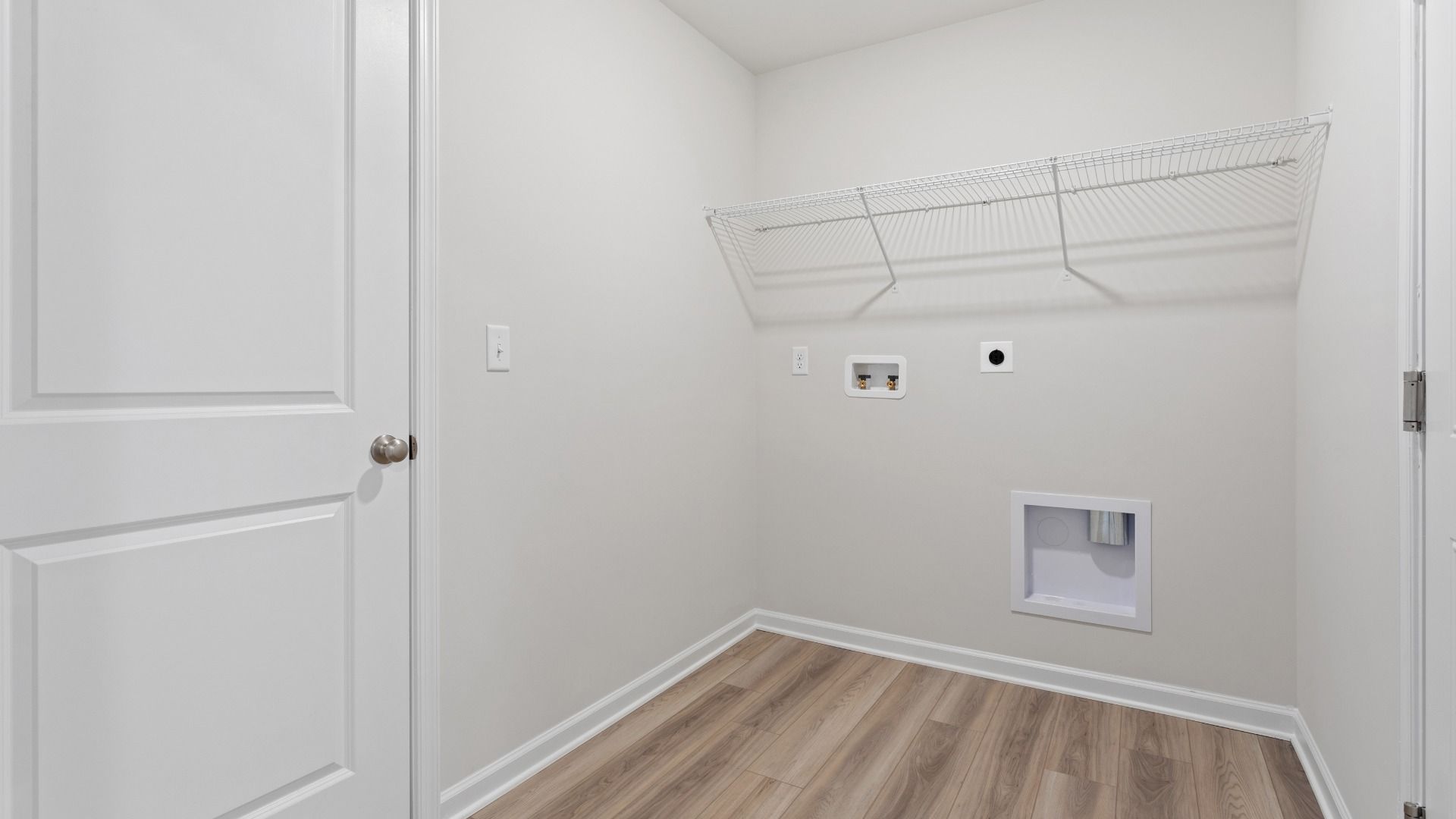 Laundry room with shelf in a DRB Homes Edgewood plan at The Village of College Park community.