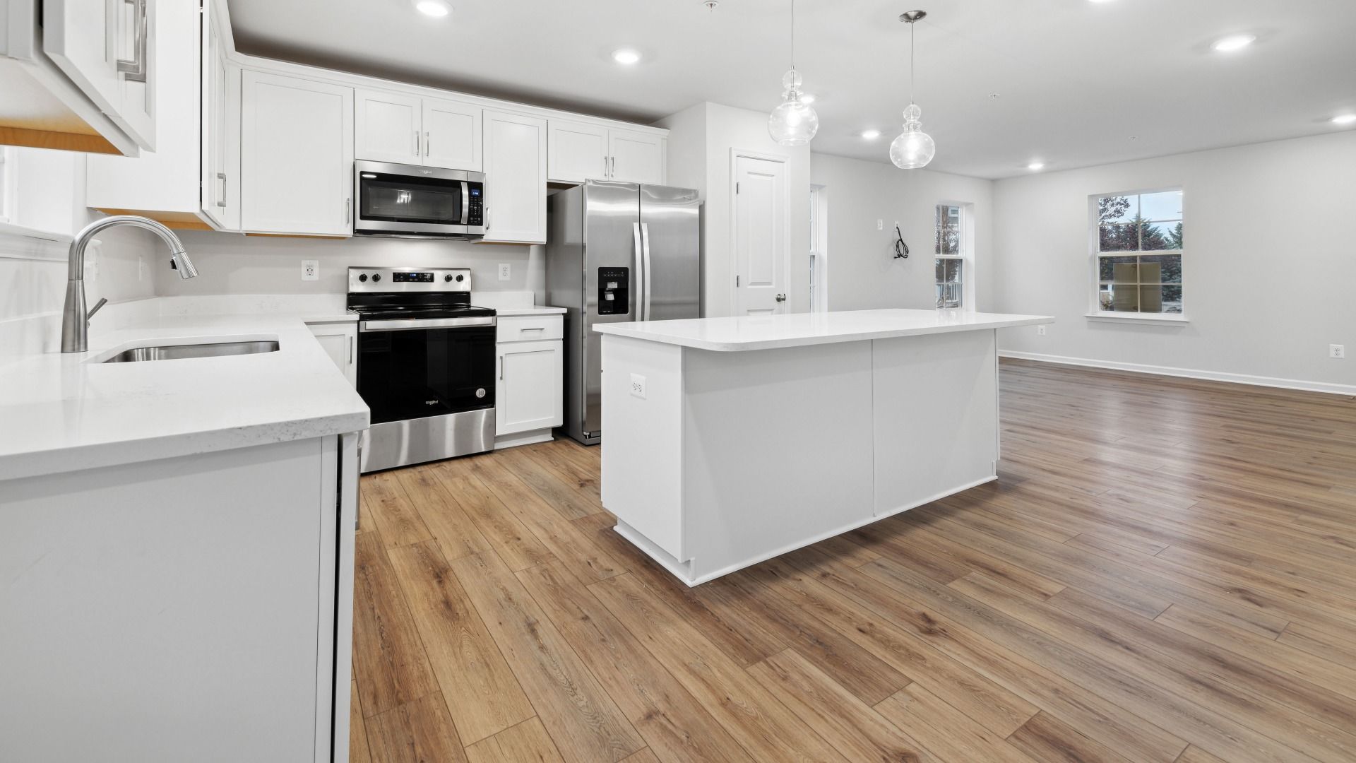 White Cabinets, Quartz Counters, and Stainless Steel Appliances in the Whitehall at Village of College Park by DRB Homes.